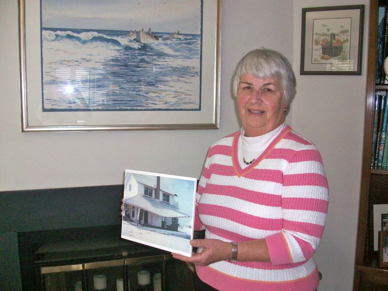 Dewey Beach Historian Barbara Dougherty displays a photograph of a house in Dewey Beach after the nor'easter of 1962. BY KARA NUZBACK